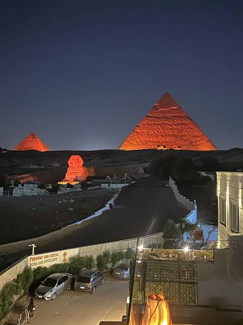 Pyramids illuminated at night with street view.