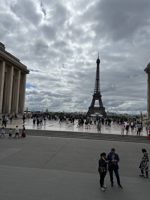       Eiffel Tower with people gathered around the plaza.
  