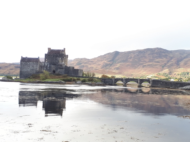 A scenic castle on a loch with mountains behind.