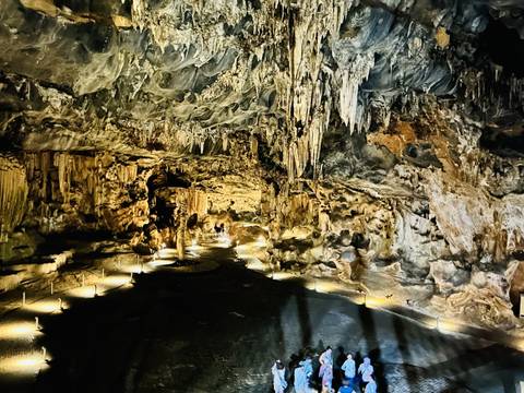 An illuminated underground cave with stalactites.
