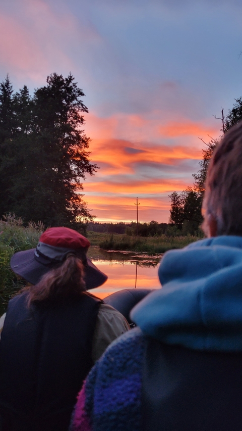       People watching a beautiful sunset over a river.
  