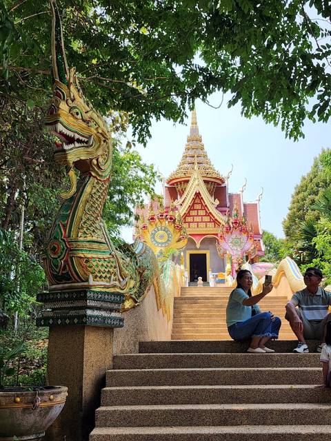 Temple entrance with naga statues and person taking a photo.