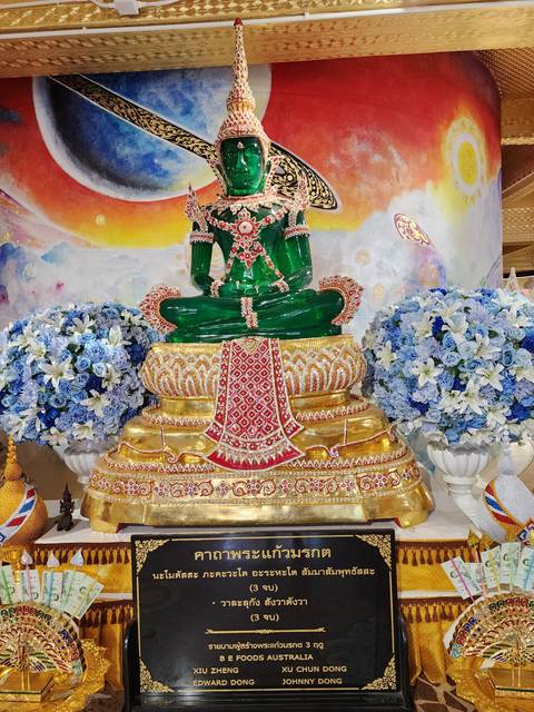 Ornate emerald Buddha statue on a decorated platform.