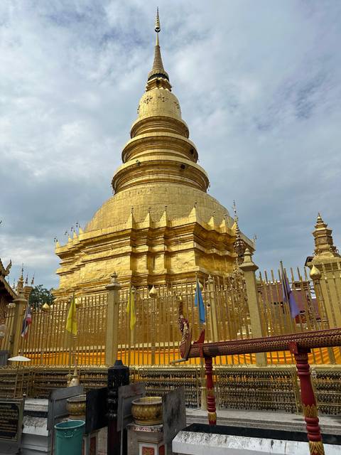 Golden pagoda with intricate design under cloudy skies.