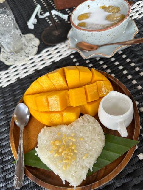 Mango sticky rice served on a wooden plate.