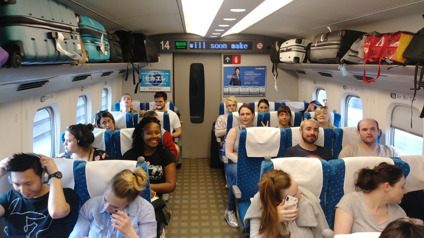 Passengers seated inside a train carriage, some using phones.