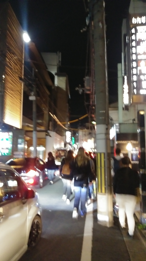       Blurred nighttime street scene with lights and people.
  