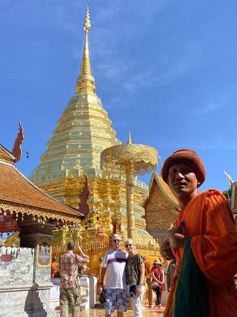 A monk and tourists at a golden temple.