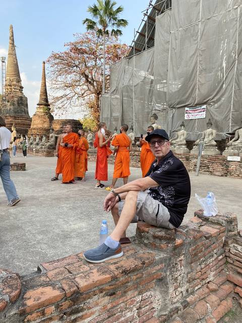       People relaxing next to monks in orange attire.
  
