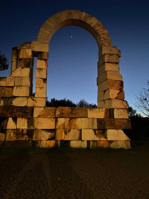 Stone arch structure with moon in the background.