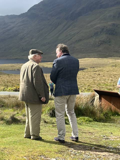 Two men outdoors, dressed in coats, conversing.