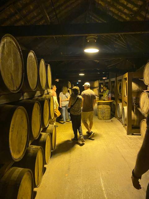 Group of people touring a warehouse with barrels.
