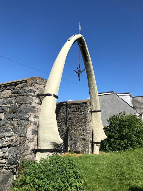 Whale bone arch acting as an entrance against a blue sky.