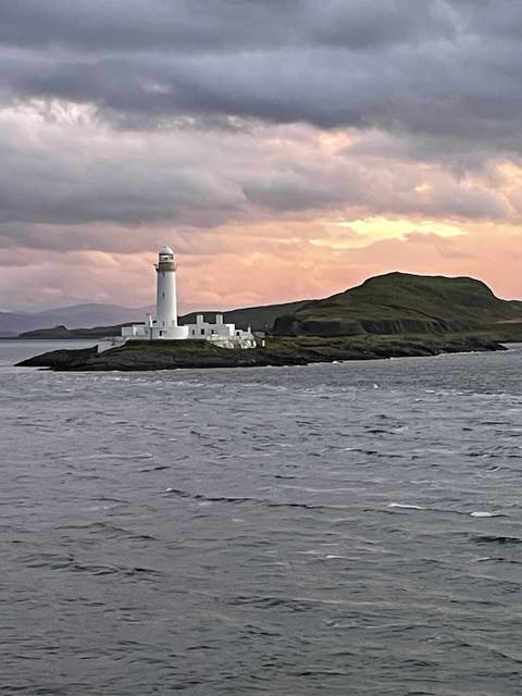       Lighthouse on a coastal scene during sunset.
  