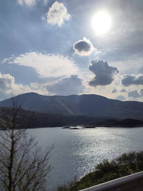       A view of a water body and mountains under the sun.
  