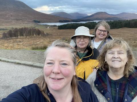       Four people posing upside down with a landscape view.
  