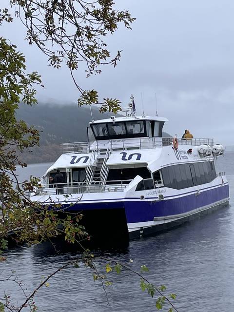       Boat on a misty lake with trees in the background.
  
