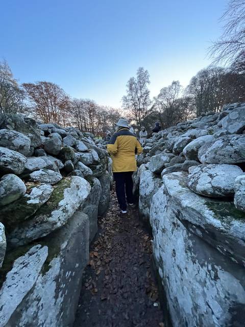       Person walking through an ancient stone structure.
  