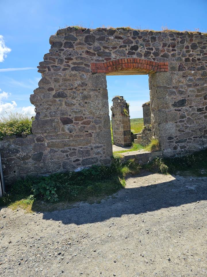 Stone ruins with an archway and grassy area.