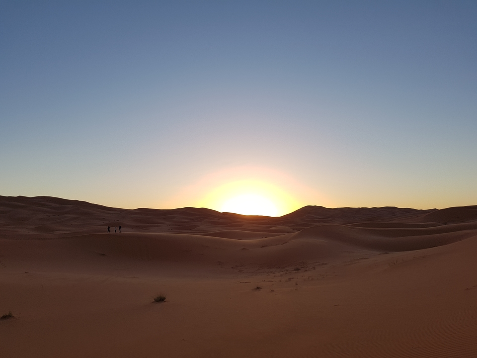 Sunset over vast sand dunes in the desert.