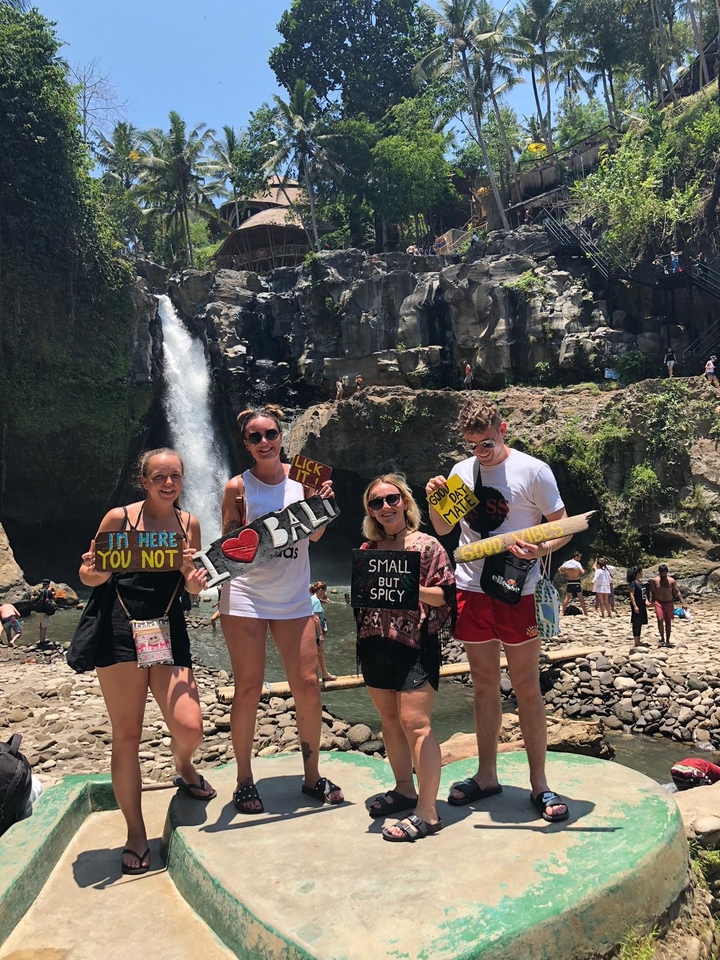 Group of people holding signs in front of a waterfall.