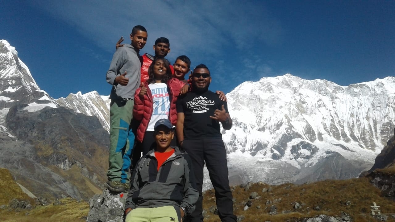 Group of people posing with snow-capped mountains in the background.
