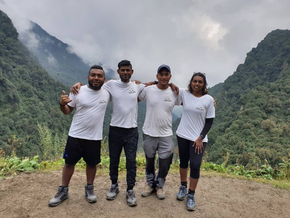 Group of people in matching shirts posing in a mountainous area.