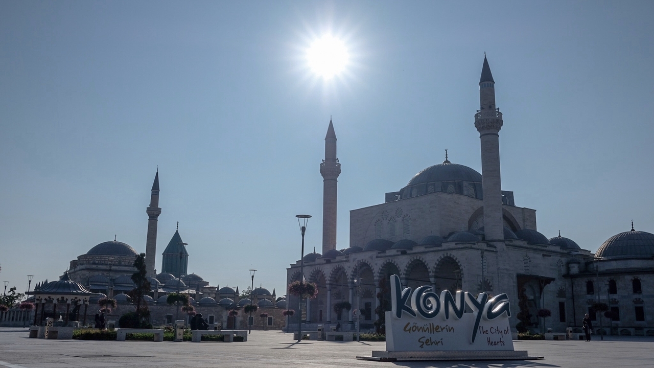 Mosque minarets under a bright sun with 'Konya' sign.