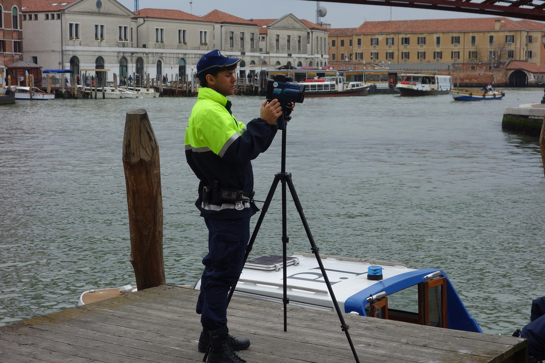 A police officer with a camera by a canal.