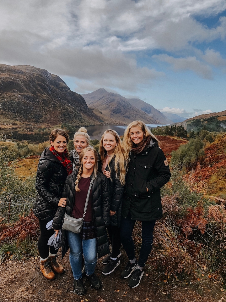 Group of women posing in front of a scenic landscapes with hills and a lake