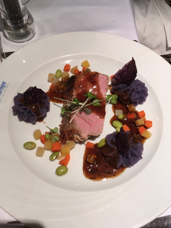 Assiette dressée avec de la viande tranchée, de la purée violette et des légumes variés.