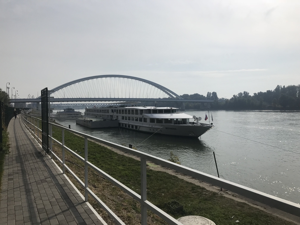 Pont moderne au-dessus d'une rivière calme avec des bateaux de croisière amarrés.