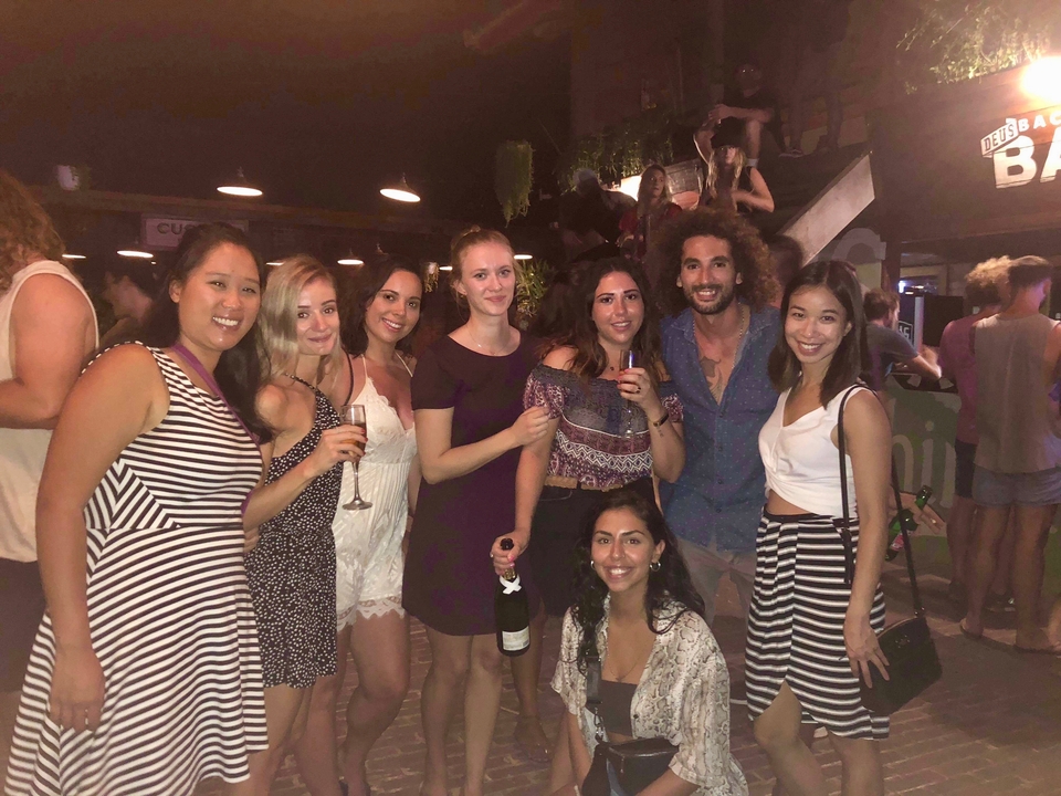 Group of people posing at a night outdoor venue with drinks.