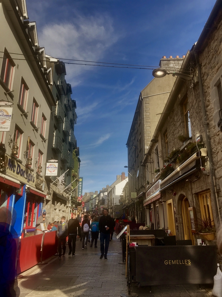 Smalle straat met historische gebouwen en hangende uithangborden.