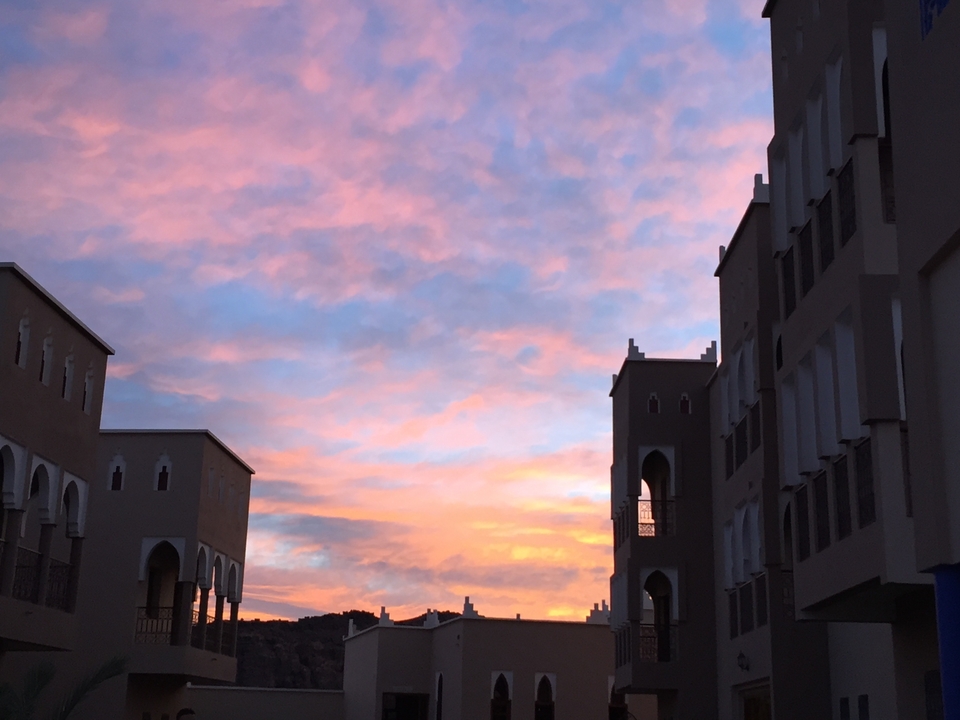 Silhouette of buildings against a colorful sunset sky.