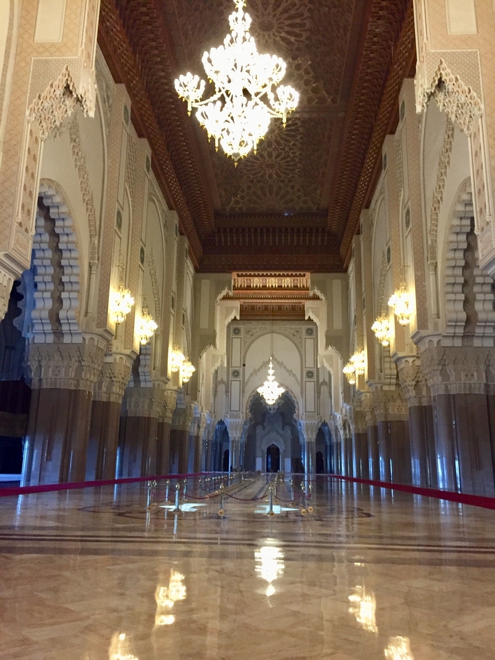 Intricate interior of a mosque with chandeliers and detailed arches.