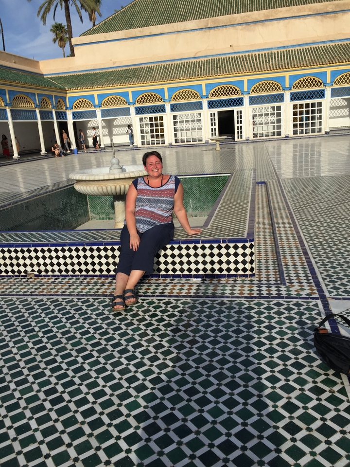 Person sitting on a decorative tiled bench at a courtyard.