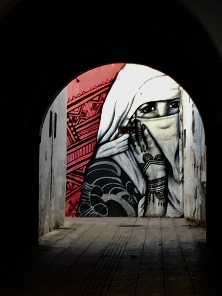 Vivid mural depicting a veiled woman with intricate patterns.