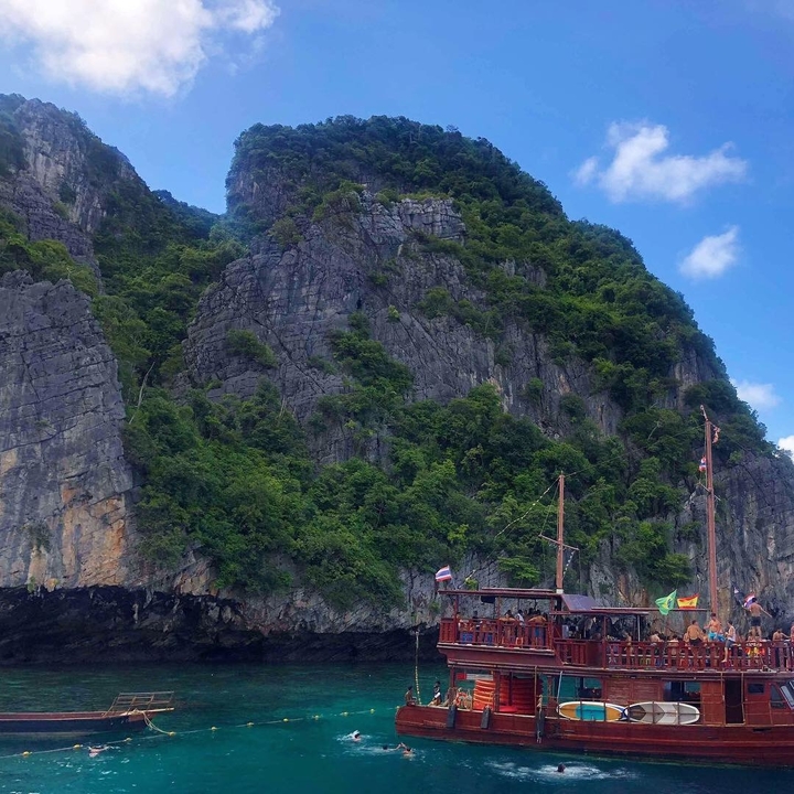 Rocky cliffside with lush greenery and a clear sky.