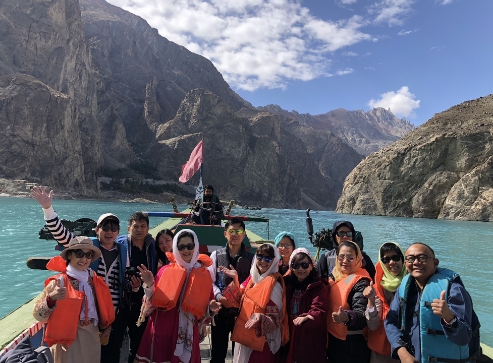Group of people on a boat in a turquoise lake surrounded by mountains.