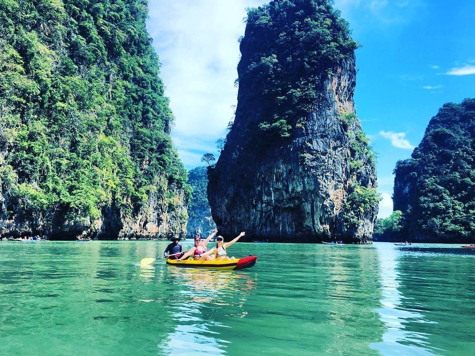 People kayaking between scenic rock formations on a calm day.