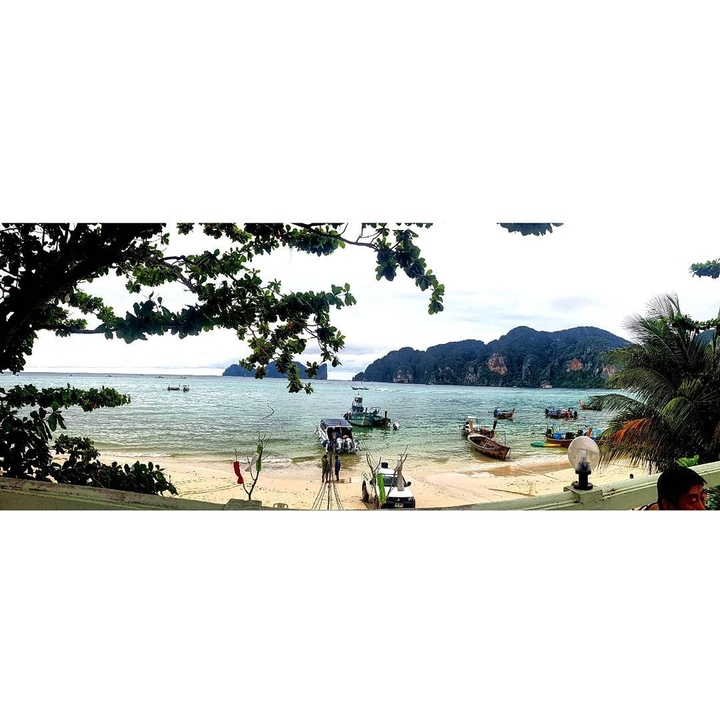 Panoramic view of a beach with boats and distant mountains.