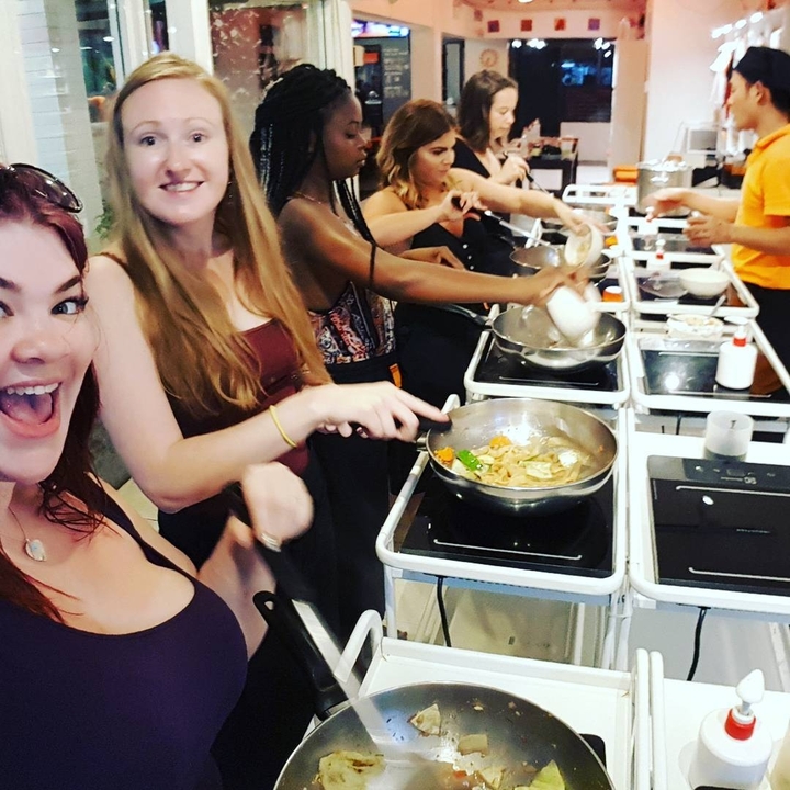 Group of people cooking together at cooking stations.