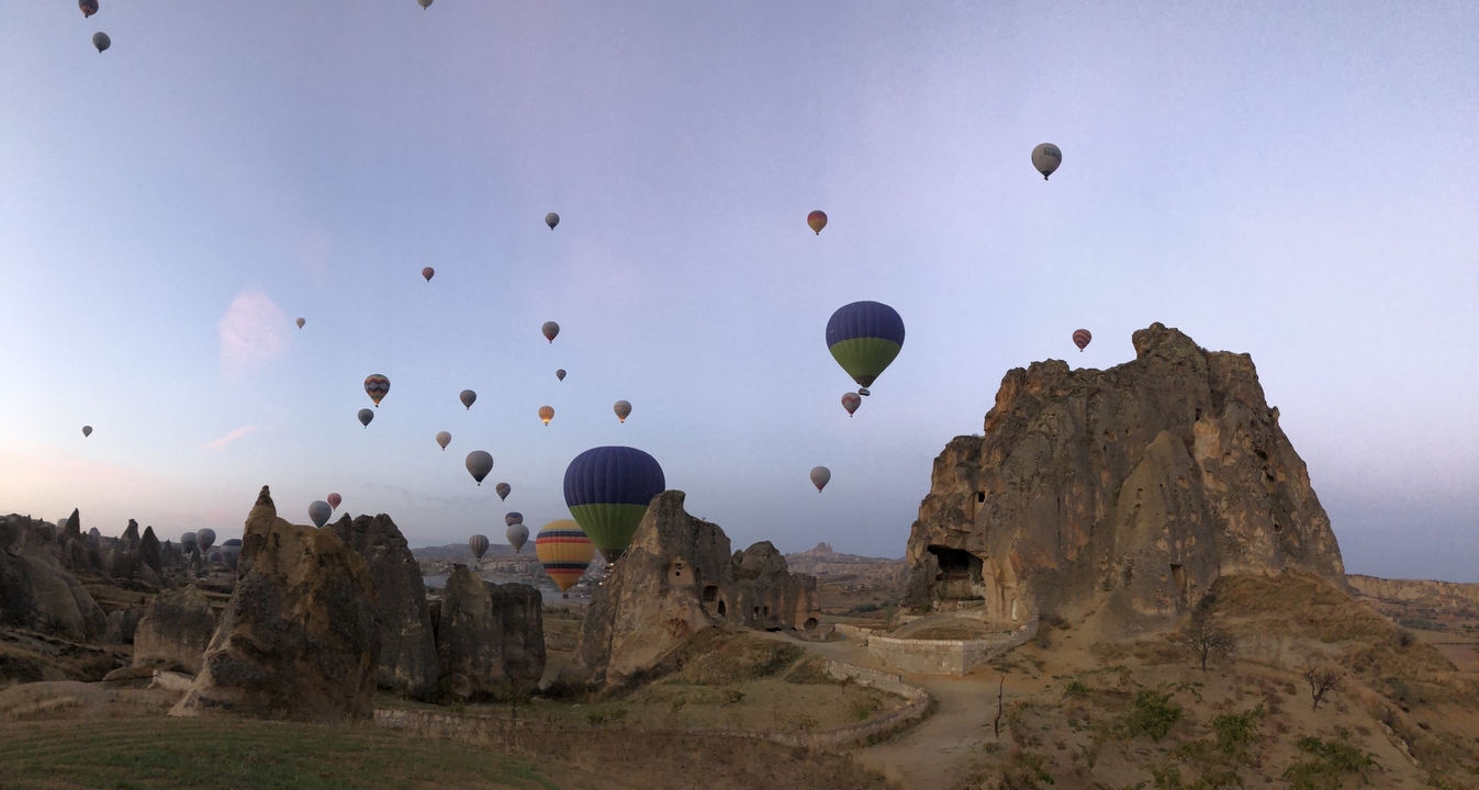 Hot air balloons flying over rocky landscape.