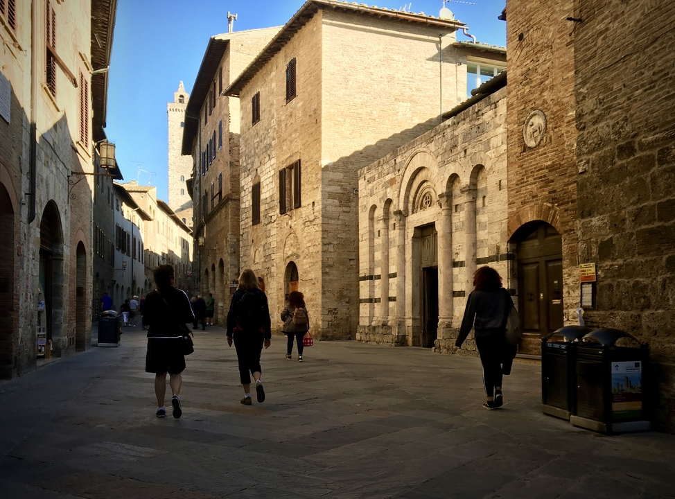 Une scène de rue avec des gens qui marchent le long d'une architecture de pierre historique.