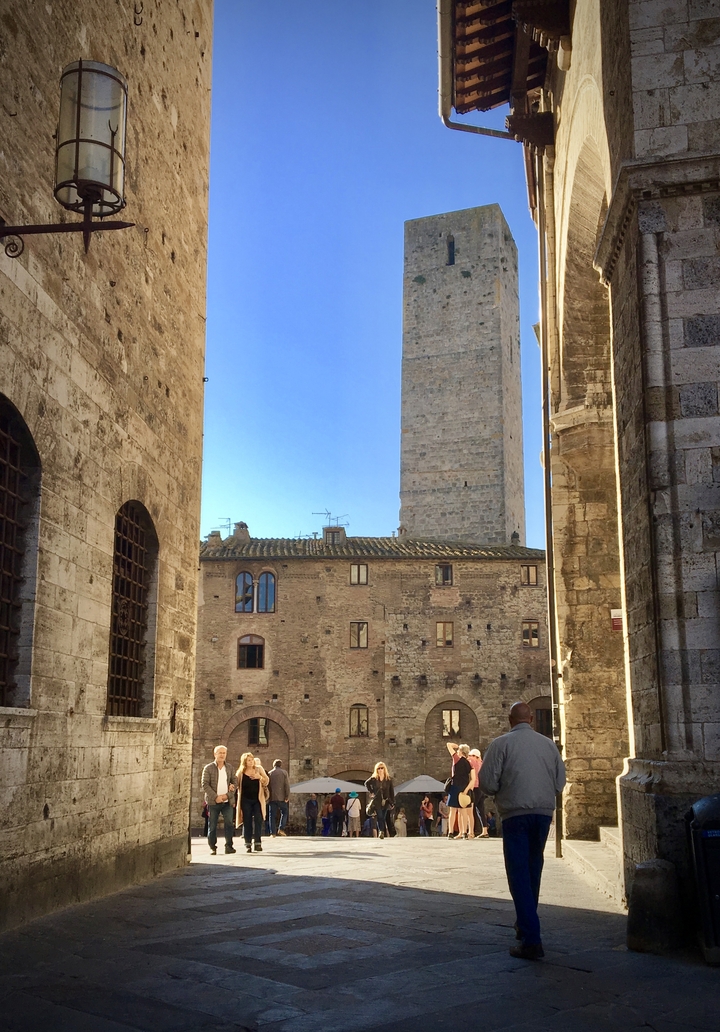 Bâtiments en pierre avec une haute tour en arrière-plan.