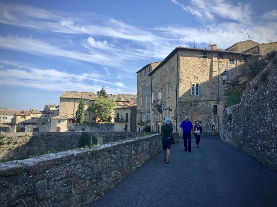 People walking along a historic stone alleyway.