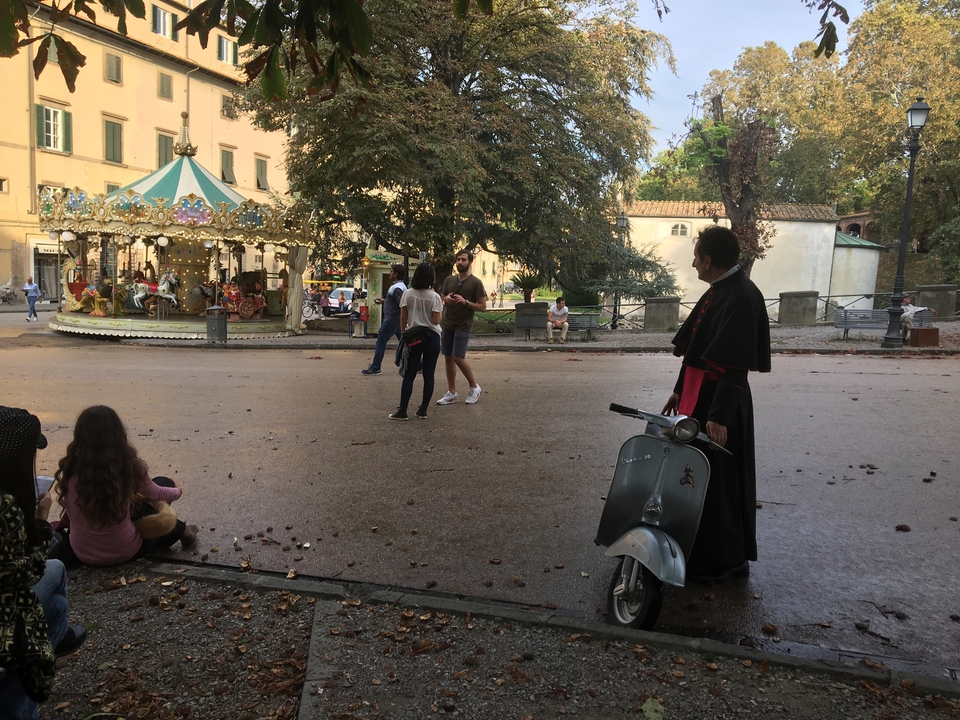 Des gens dans un parc avec un manège et un vieux scooter.