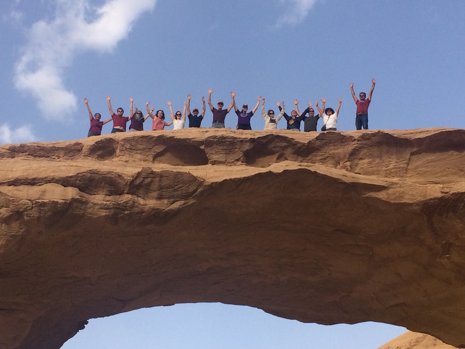 Group of people raising hands on a cliff.