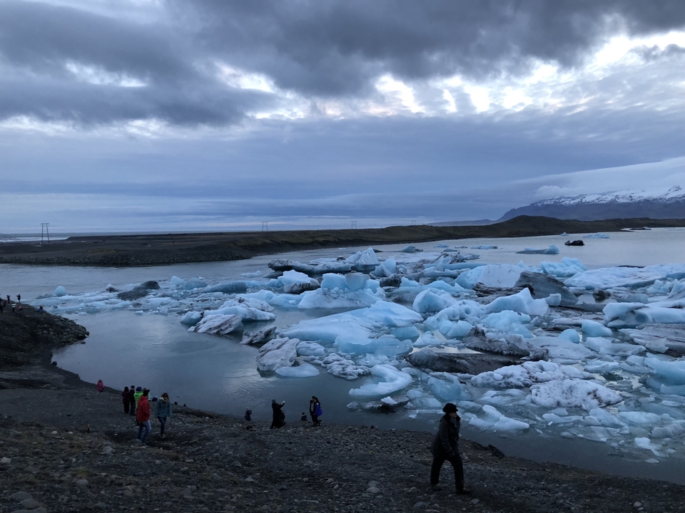 Icebergs floating in a lagoon with people observing.